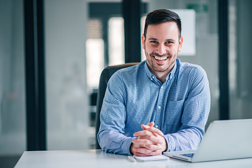 Portrait of a smiling entrepreneur or businessman at office desk.