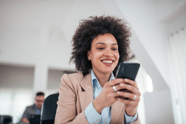 istock Smiling african american businesswoman using smart phone in co working office, low angle view. 1139864600