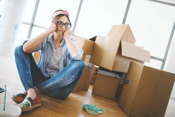 Moving in can be quite exhausting. Young woman sitting on the floor, tired of all the work that she done by herself at her apartment. eviction photos stock pictures, royalty-free photos & images