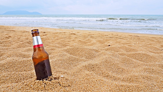 Beer bottle on the beach. For advertising of summer holiday or concepts of no garbage on beach background.