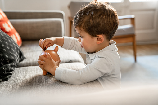 Boy putting coins on piggy bank