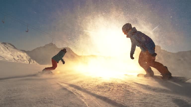 SPEED RAMP Two snowboarders riding towards the setting sun