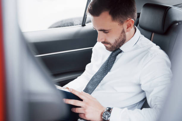 istock A young businessman arranges his affairs with a notepad while sitting in the car's back 1139870616