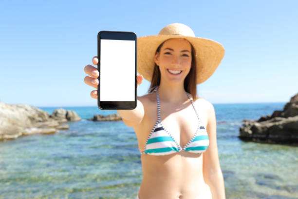 Tourist showing blank vertical phone screen on the beach
