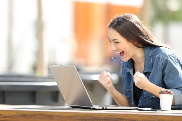 istock Excited woman checking laptop content in a park 1139872144