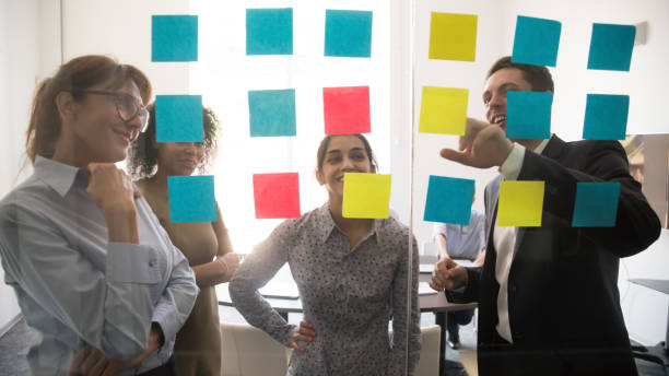 istock Diverse team people looking at sticky notes on glass brainstorming 1139873804
