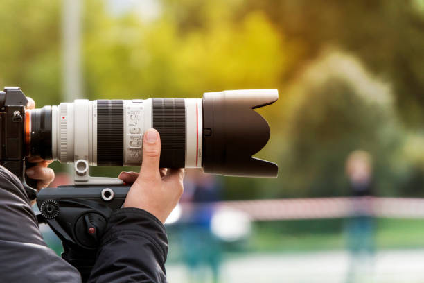 processus de prise de photos à l'extérieur. photographe professionnel zoome pour faire un coup. l'homme tire avec une lentille moderne à l'extérieur. tir avec l'objectif. paparazzi avec objectif haut de gamme. compétences photographiques. - eyes narrowed photos et images de collection