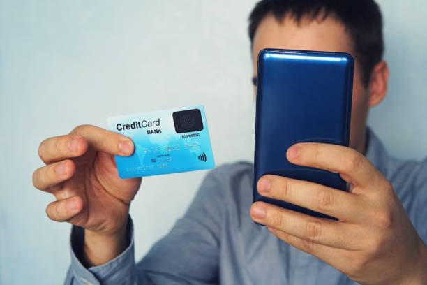 Close up of male in shirt making online payment via plastic card and smart phone. Unrecognizable man holding mobile and credit card with biometric system. Online banking. E-commerce. Purchase. Bank. Close up of male in shirt making online payment via plastic card and smart phone. Unrecognizable man holding mobile and credit card with biometric system. Online banking. E-commerce. Purchase. Bank cvc stock pictures, royalty-free photos & images