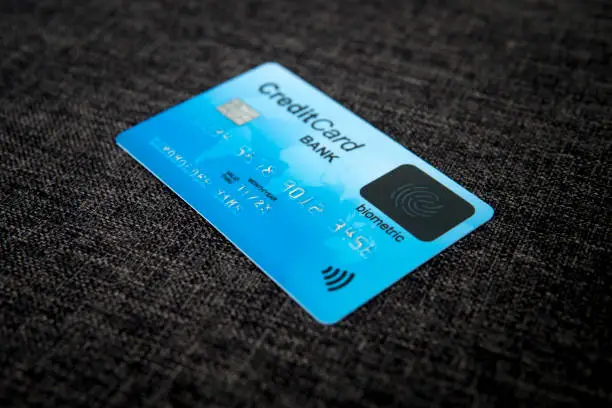 Close up of credit card with new fingerprint recognizing technology at sackcloth material background. Card with electronic chip, cardholder data and biometric sign on its face. Biometrics in banking
