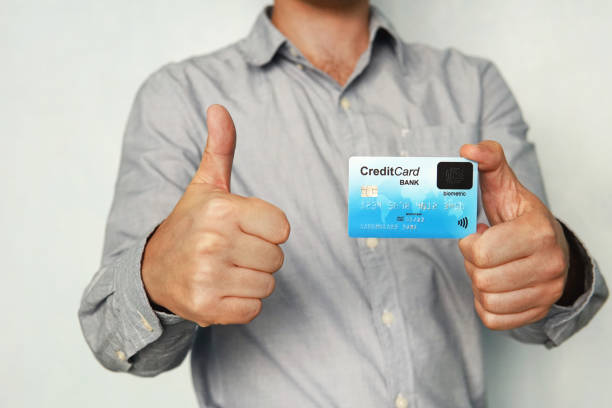 Man holding credit card with built-in fingerprint scanner and showing thumb up. Concept of safe payment without pin code. Biometric banking. Man is satisfied with using new technology. Touch sensor hombre sosteniendo tarjeta de crédito con escáner de huellas dactilares incorporado y mostrando el pulgar hacia arriba. concepto de pago seguro sin código pin. banca biométrica. el hombre está satisfecho con el uso de la nueva tecnología. sensor tác