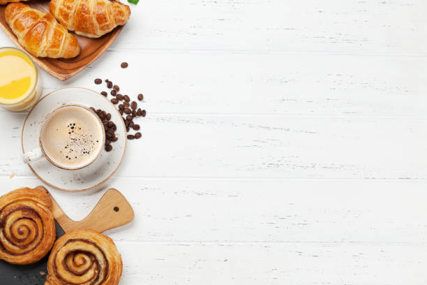 Coffee, juice and croissants breakfast Coffee, croissants, orange juice, cinnamon rolls and berries breakfast. On wooden table. Top view with copy space for your text croissant stock pictures, royalty-free photos & images