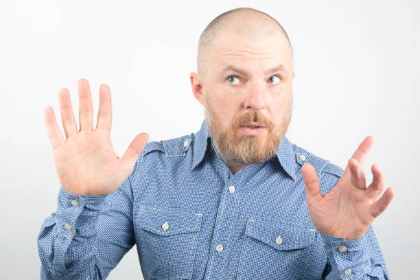 istock Bearded man in blue shirt with raised arms on a light background 1139881612