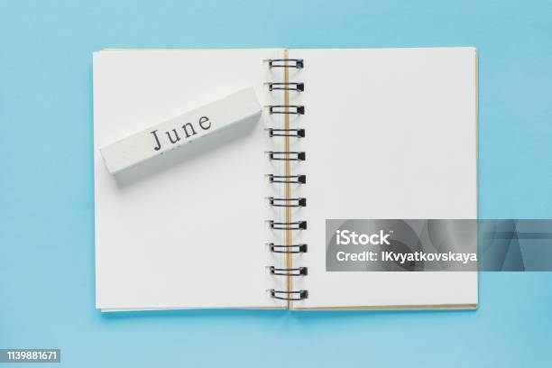Clean Spiral Note Book For Notes And Messages And June Wooden Calendar Bar On Blue Background Minimal Business Flat Lay Stock Photo - Download Image Now