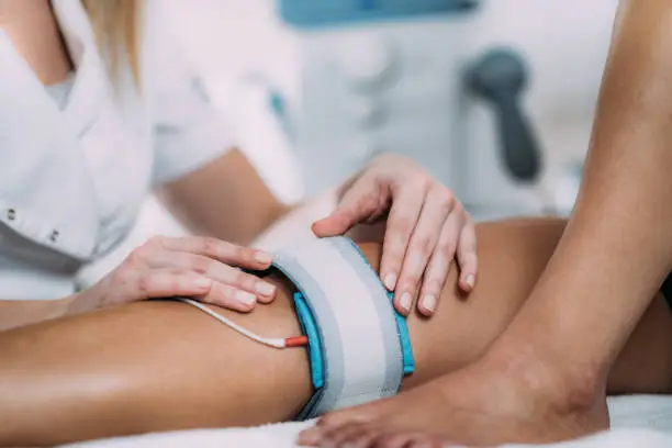 TENS, Transcutaneous Electrical Nerve Stimulation in Physical Therapy. Therapist Positioning Electrodes onto Patient's Knee