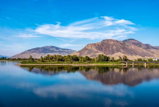 Thomson River, Kamloops, BC with mountain range and railway bridge in distance.