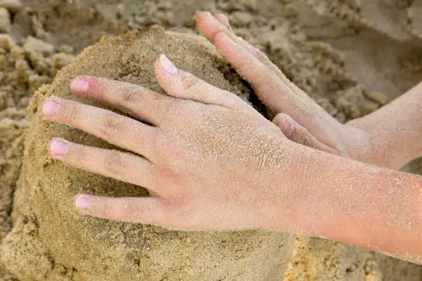Human hands sculpt from the sand, summer time
