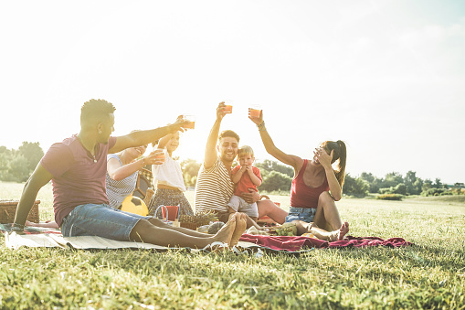 Familias felices haciendo picnic en Natur Park-padres jóvenes divertirse con sus hijos en verano comiendo, bebiendo y riendo juntos-concepto de amor y chlidood-enfoque principal en la cara izquierda del hombre photo
