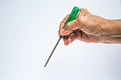 Senior Woman's right hand holding old green screwdriver on white background, Construction building and repair tool concept