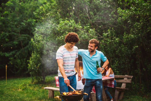 A Caucasian father and a daughter preparing a barbecue at a family picnic in the forest
