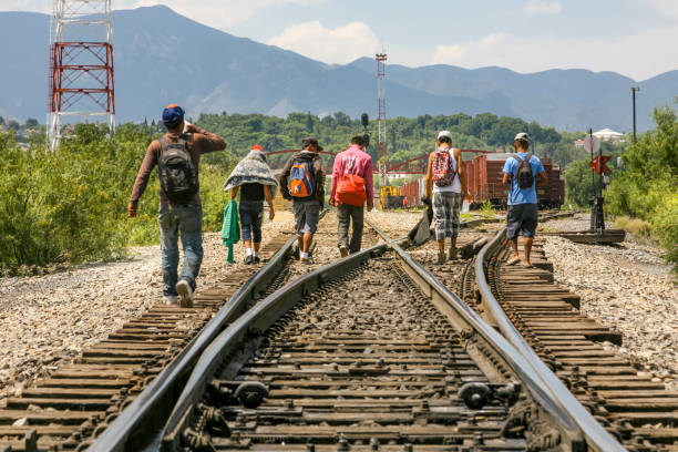 A group of migrants walk along the railroad near the US-Mexico border in the state of Coahuila in northern Mexico Coahuila, Mexico, Jun 16 - A group of migrants of Central American origin waits on the railway line to get on a container train, known as 'The Beast', to go to the border of the United States and Mexico, between the states of Coahuila (Mexico) and Texas (USA). immigrant stock pictures, royalty-free photos & images