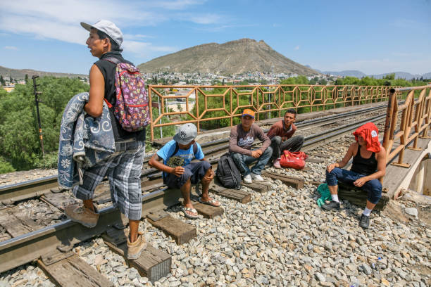 Some migrants rest along the railroad near the US-Mexico border in northern Mexico Coahuila, Mexico, Jun 16 - A group of migrants of Central American origin waits on the railway line to get on a container train, known as "The Beast", to reach the border line between the United States and Mexico. railway bridge photos stock pictures, royalty-free photos & images