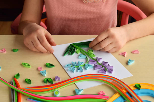 istock Quilling technique. Girl making decorations or greeting card. Paper strips, flower, scissors. Handmade crafts on holiday: Birthday, Mother's or Father's Day, March 8, Wedding. Children's DIY concept. 1139897198