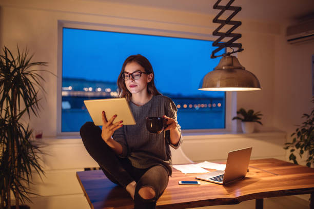 Beautiful content creator drinking coffee and relaxing at home reading about taxes