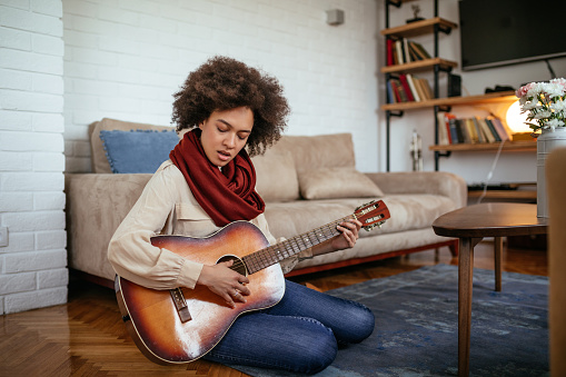 Beautiful girl playing a guitar at home.