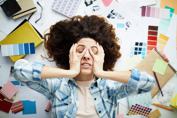 Tired Freelancer Top view portrait of exhausted designer lying in pile of work with eyes closed, copy space publisher photos stock pictures, royalty-free photos & images
