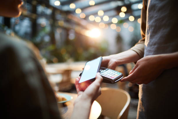 Making online payment in cafe Close-up of unrecognizable woman using modern gadget while making online payment in cafe, nfc technology concept paying stock pictures, royalty-free photos & images