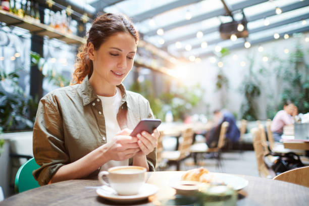 una mujer guapa revisando al mensajero en el café - restaurant review fotografías e imágenes de stock