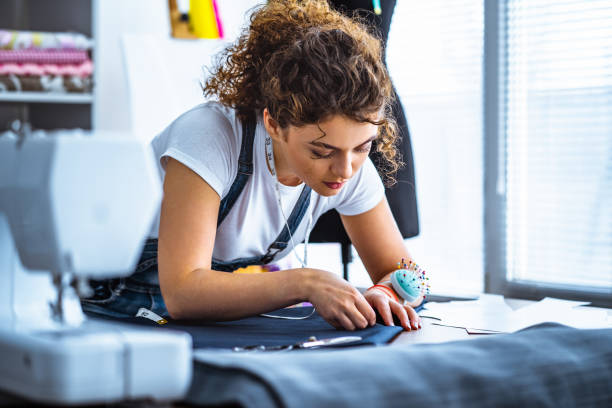 le jeune tailleur travaillant près de la machine à coudre - fashion industry photos et images de collection