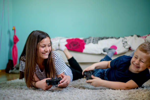 Two teenagers playing video games sitting on a sofa, illuminated by a pink light