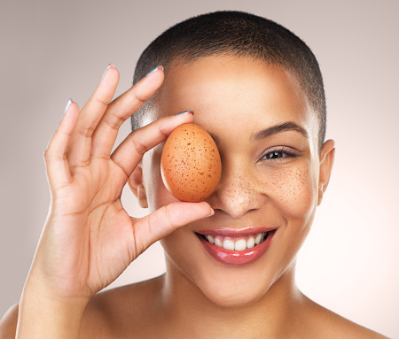 Studio shot of a beautiful young woman holding a egg against her face
