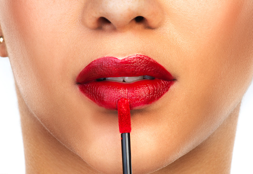 Cropped shot of an unrecognizable woman applying red lipstick to her lips