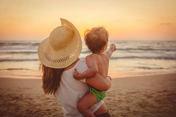 istock Mother with son enjoying sunset on the beach 1139909632