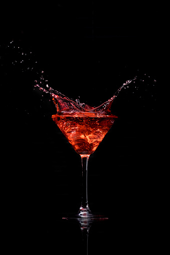 Ice drops into a a martini glass creating a splash