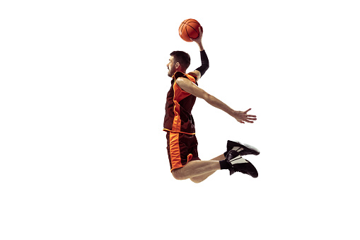 Full length portrait of a basketball player with ball isolated on white background. Advertising concept. Fit caucasian athlete jumping at studio. Motion, activity, movement concepts.