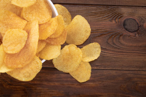 istock Crispy potato chips in bowl on wooden background, top view 1139911616