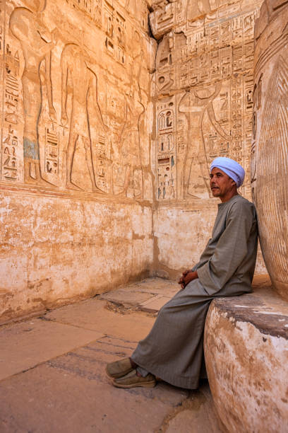 Egyptian man resting in ancient temple, Egypt Egyptian man looking at hieroglyphs in ancient temple and admires , Egypt medinet habu stock pictures, royalty-free photos & images