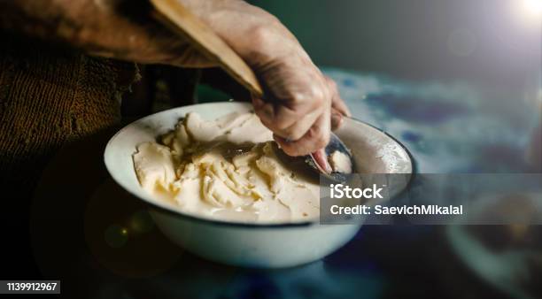 Hands Of An Old Woman With A Wooden Spoon Whip Homemade Butter With Whey Stock Photo - Download Image Now