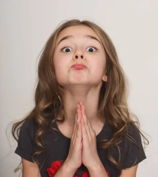 Photo of Little girl pleading with hands clasped together