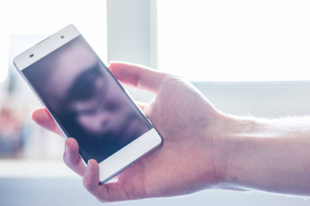 istock Smart phone in the hand, reflection of a face on the black display 1139917116