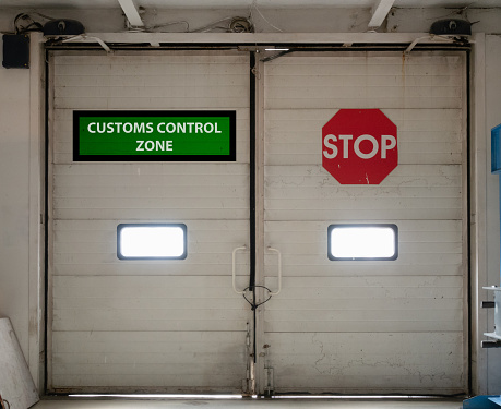 customs control zone automatic gates doors inside security check area with vivid red stop sign. concept of closed border for import or export