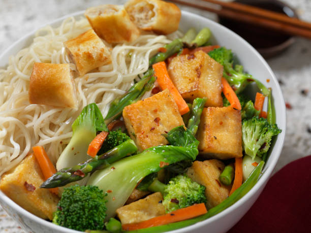 bol de nouilles au tofu avec rouleau de printemps végétal - pâtes au chou chinois et au tofu photos et images de collection