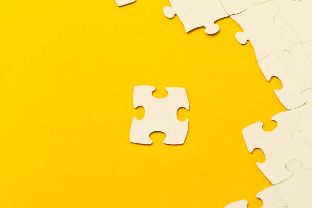 istock White jigsaw puzzles on yellow background. The concept of development of thinking. 1139928356