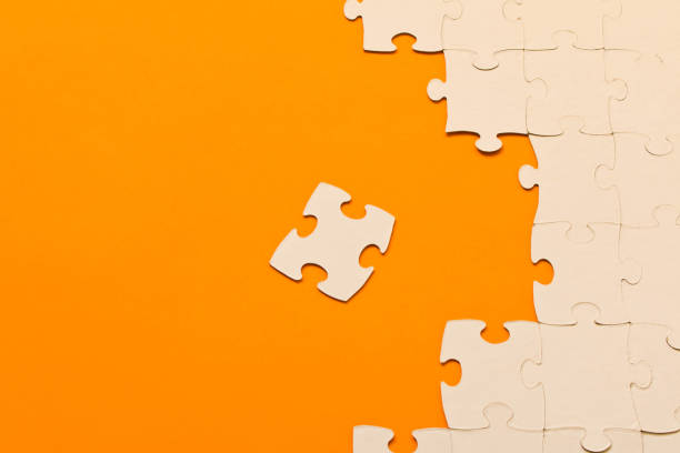 istock White jigsaw puzzles on orange background. The concept of development of thinking. 1139928920