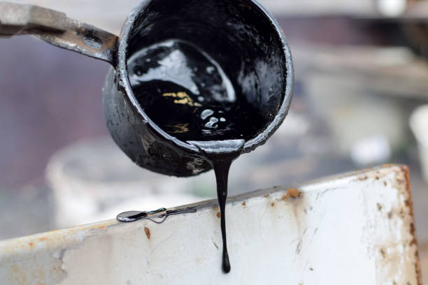 istock Melted hot black tar from metal cup on surface with steam 1139929133