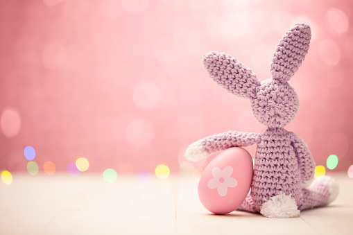Cute homemade Easter bunny with egg on a pastel pink background