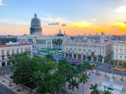 Top view of National Capitol Building (El Capitolio) and the central park during sunset in the old Havana, Cuba. City-center park with palm trees, fountains, paths & benches surrounding a statue of José Martí. Famous sightseeing location for tourist.